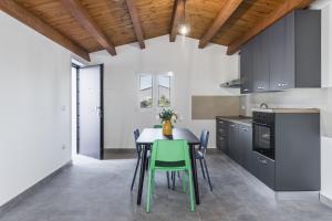 a kitchen with a table with green chairs at Casa nel Verde a Fontane Bianche by Wonderful Italy in Siracusa