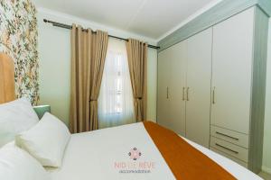 ein Schlafzimmer mit einem weißen Bett und einem Schrank in der Unterkunft Nid de Rêve Accommodation in Midrand