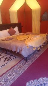 a bedroom with a large bed with a canopy at Dunes luxury camp in Merzouga