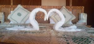 two white swans sitting on top of a bed at Dunes luxury camp in Merzouga