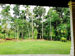 uma vista para um campo de relva com palmeiras em JAYANDRA HOLIDAY BUNGALOW 