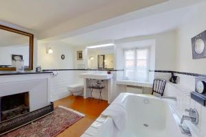 een witte badkamer met een bad en een open haard bij La Maison du Prince in Grimaud +26 foto's
