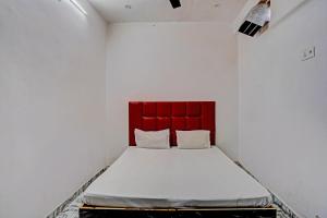 a bed in a white room with a red headboard at OYO Moon Murad Ganj in Auraiya