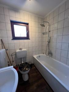 La salle de bains est pourvue d'une baignoire, de toilettes et d'une fenêtre. dans l'établissement Secrets Design Apartment, à Rodenbach
