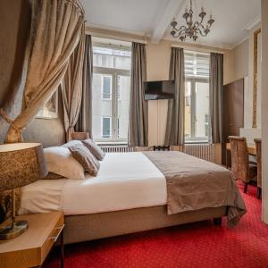 Hotel Van Eyck في بروج: غرفة نوم بسرير كبير مع سجادة حمراء