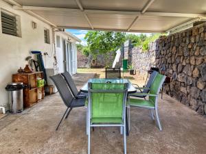 a table and chairs on a patio with a stone wall at Villa détente vue mer st leu 6 personnes in Saint-Leu