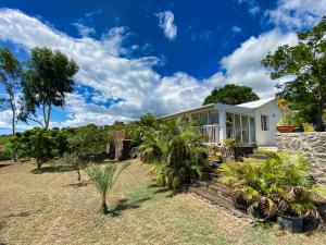 a white house with plants in front of it at Villa détente vue mer st leu 6 personnes in Saint-Leu