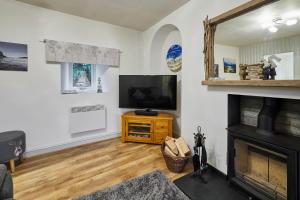 a living room with a television and a fireplace at Host & Stay - Camwy Cottage in Brynsiencyn