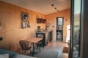 a room with a table and a kitchen with wooden walls at Tiny House Morvan Bourgogne nature - 2h de Paris in Bussières