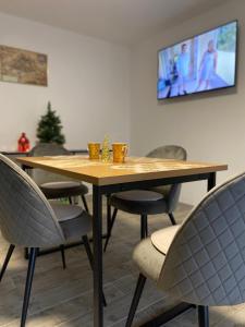 a wooden table with chairs and a tv on a wall at Sunny Hill Apartments in Sînpetru