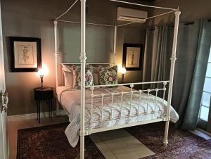una camera con letto a baldacchino bianco e cuscini di Cafe Felix & Old Oak Manor a Riebeek-Kasteel