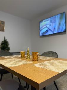 uma mesa de madeira com três copos e uma televisão na parede em Sunny Hill Apartments em Sînpetru