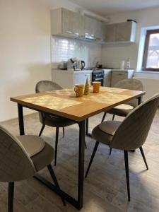 uma mesa de madeira e cadeiras numa cozinha em Sunny Hill Apartments em Sînpetru