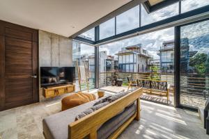 a living room with a large window and a television at Divine 1BR PH Tulum w Private Pool, Cenote, Gym in Tulum