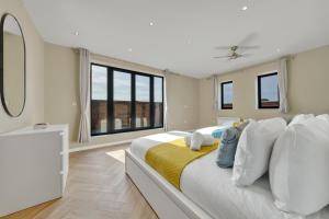 een witte slaapkamer met een groot bed met een gele deken bij OYO Fine B&B in Hanwell