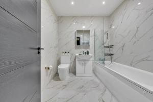 a white bathroom with a tub and a toilet and a sink at OYO Fine B&B in Hanwell