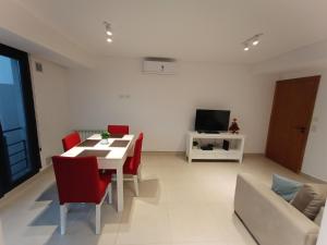een woonkamer met een tafel en stoelen en een televisie bij Valle Serrano II Departamentos in Tandil