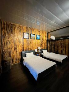 Duas camas num quarto com paredes de madeira em Thênh Thang Home & Cafe em Mộc Châu
