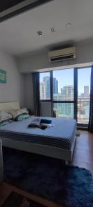 a bedroom with a bed with a large window at Aveline Suites Cozy Skyline View ACQUA Private Residences near Rockwell Makati in Manila