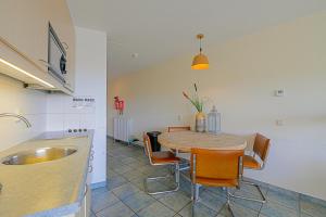 cocina y comedor con mesa y sillas en Appartement Wijde Blick 207 - aan de duinen - Callantsoog, en Callantsoog