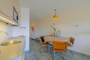 a kitchen and dining room with a table and chairs at Appartement Wijde Blick 207 - Callantsoog aan Zee in Callantsoog +23 photos