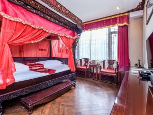 - une chambre avec un lit à baldaquin et des rideaux rouges dans l'établissement ChengDu Wuhou Temple Han Dynasty Hotel, à Chengdu