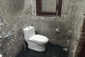 a bathroom with a white toilet and a mirror at Greenleaf Apartment and Suites, Kalkaji in New Delhi