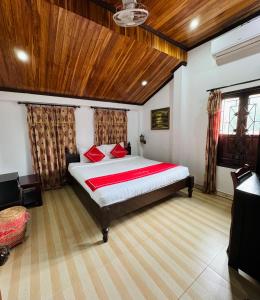 una camera da letto con un grande letto con cuscini rossi di Singharat Boutique House a Luang Prabang