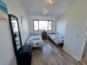 a small room with two beds and a mirror at 24 Arniston Village, Melkbosstrand in Melkbosstrand