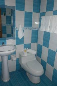 a blue and white bathroom with a toilet and a sink at Hotel Venecia in Huánuco
