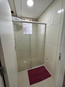 ducha con puerta de cristal y toalla púrpura en Kitnet 5, en Rio Negrinho