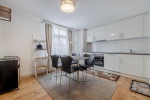 a kitchen with white cabinets and a table and chairs at Mama Home Apartment W26 in St. Gallen