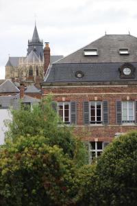 un bâtiment en briques avec une tour d'horloge en arrière-plan dans l'établissement O DELA DE L'O, LE 64 - maison d'hôtes de charme entre Côte d'Albâtre et Baie de Somme, à Eu