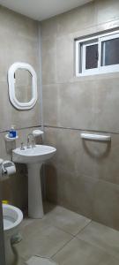 a bathroom with a sink and a toilet and a window at Hostal del Sol Rosario in Rosario