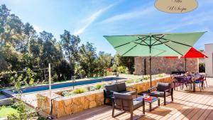 un patio con una mesa y una sombrilla verde en Villa U Scopu, 6 pers, piscine chauffée, 10 mn plage en voiture, en Lecci