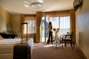 a woman standing in a hotel room looking out the window at Europe Hotel in Sofia +78 photos