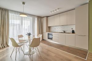 uma cozinha com armários brancos e uma mesa e cadeiras em Alternativ 3 Residence Central em Timisoara