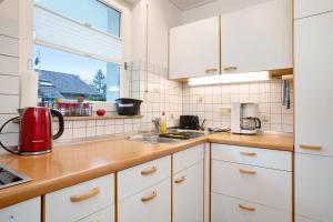 uma cozinha com armários brancos, um lavatório e uma janela em Haus Loser em Wasserburg