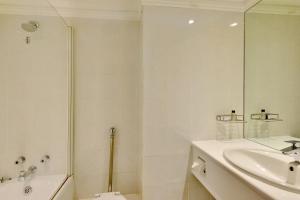 a white bathroom with a sink and a shower at The Capetonian - Halaal in Cape Town