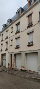un edificio de apartamentos con cuatro puertas de garaje en una calle en Le Déodatien, en Saint-Dié-des-Vosges
