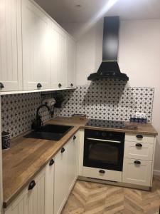 a kitchen with white cabinets and a sink and a stove at Apartament Frezja in Gryfów Śląski