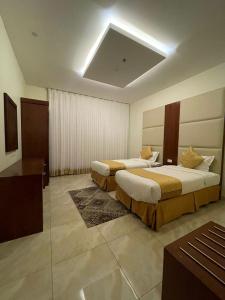 una camera d'albergo con due letti e una televisione di Rayat Al Shalal Hotel a Hafr Al Baten