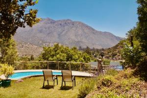 two chairs and a pool with a mountain in the background at Loft de montaña Los Guayacanes in San José de Maipo