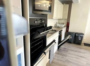 een keuken met een zwarte kachel en een magnetron bij Horizon House, Stunning 2-Bedroom Flat 1, Parking, Netflix, Oxford in Oxford