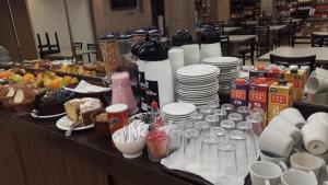 a buffet with plates and glasses and food on a table at Hotel Maravilha in Caçapava do Sul +17 photos