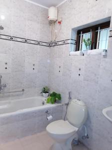 a white bathroom with a toilet and a bath tub at Surendram Villa in Varkala