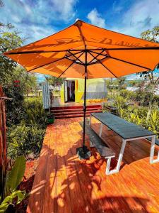 a bench under an orange umbrella on a deck at Kravanh Camping Cardamom Mountain in Véal Vêng