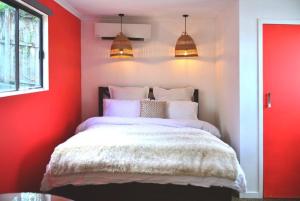 1 dormitorio con paredes rojas y 1 cama con sábanas blancas en Bulimba Studio en Brisbane