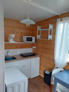 una cucina con mobili bianchi e un forno a microonde di Le petit chalet a Chanas