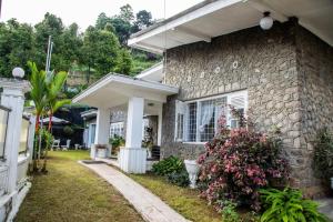ein Steinhaus mit einem Garten mit Blumen in der Unterkunft Funk Bunks - By The Lake in Kandy